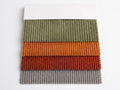 Corduroy fabric swatches in olive green, orange, clay red and gray, fanned out on a white card